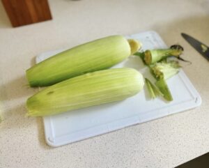 Cut both ends of the corn to fit into the pan.